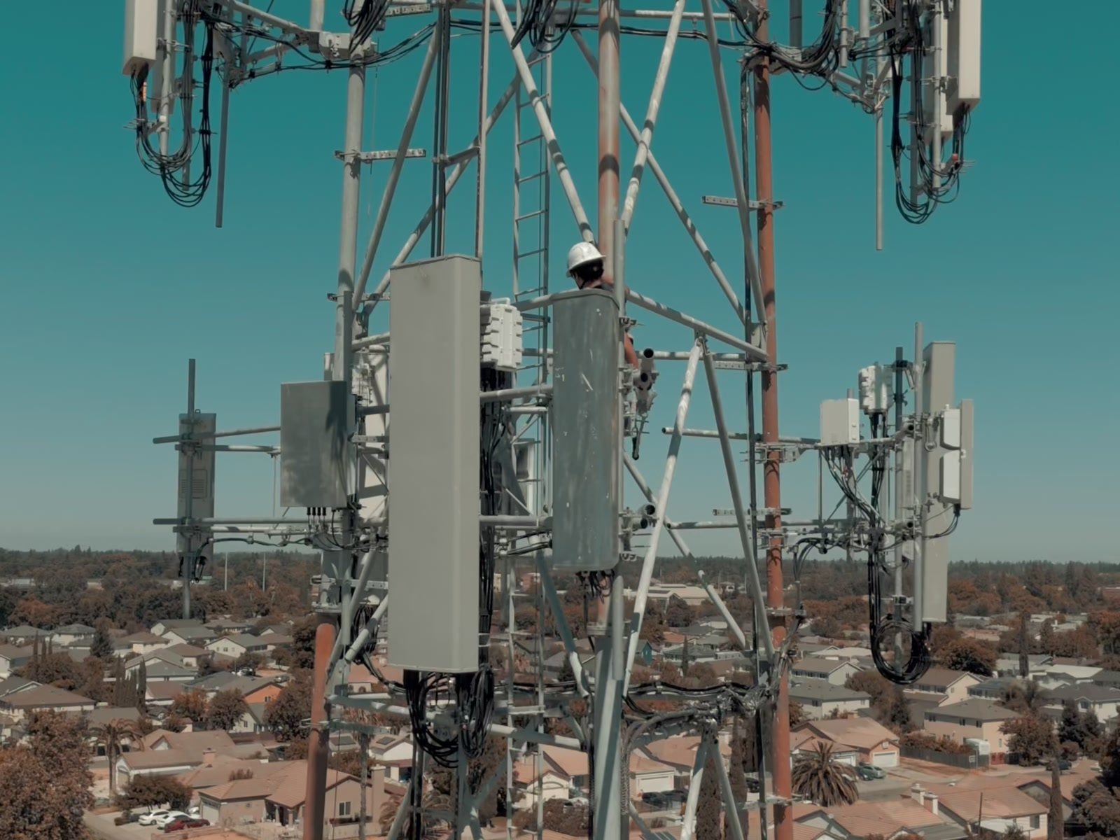 Close aerial inspection of cellular antenna array with technician at height